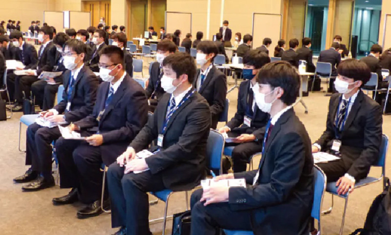 写真：KCS合同企業説明会の様子。スーツを着たたくさんの学生が会場で企業説明を聞いている。