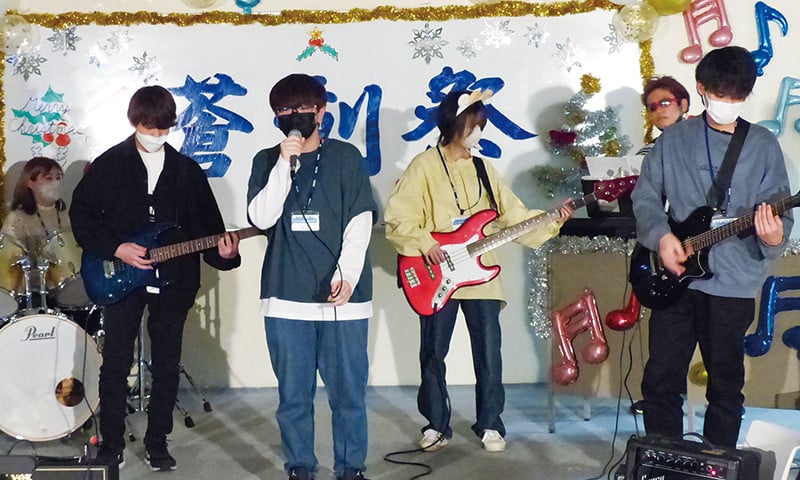 写真：蒼造祭でのバンド演奏の様子。バンドメンバーは6人で、その後ろ側、飾りが付けられたホワイトボードに「蒼造祭」と書かれている。