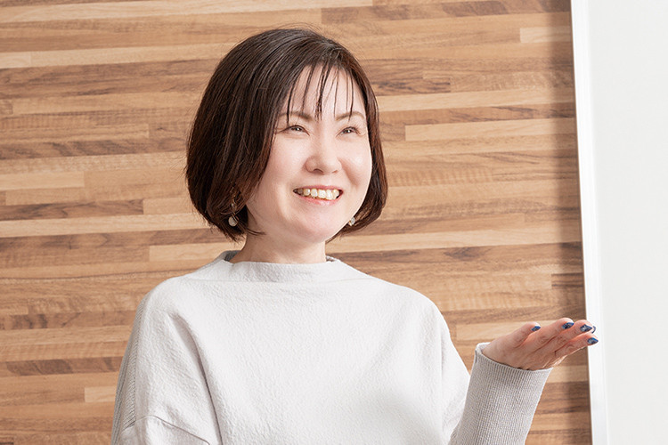 写真：白いブラウスを着たショートカットヘアーで笑顔の女性