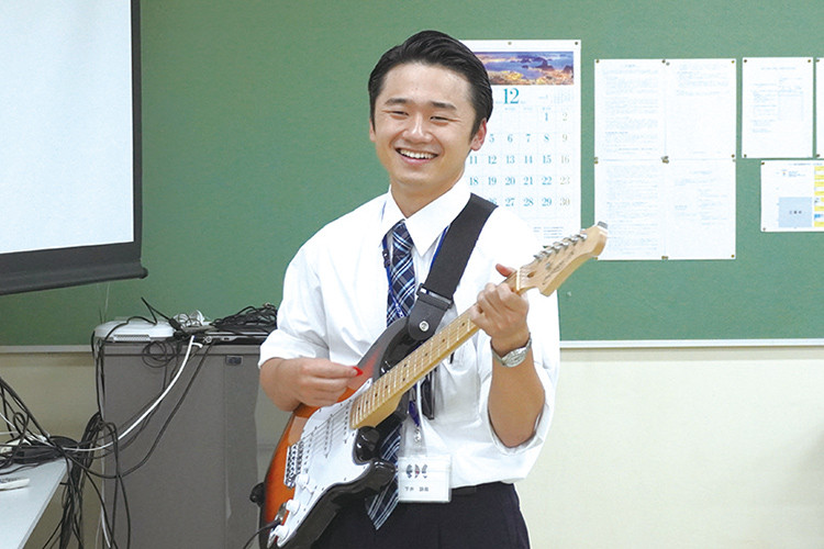 写真：楽しそうにギターを演奏している下井 諒哉先生