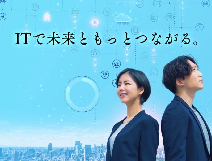 ITで未来ともっとつながる。 IT技術と未来がつながっていく様子を想起させるイメージ画像。都市の街並みの風景写真にIT技術でよく使われるアイコンが組み合わされており、ジャケットを着た若い男女が背中を向け合って立ち、視線を遠くに向けて希望にあふれる表情をしている。