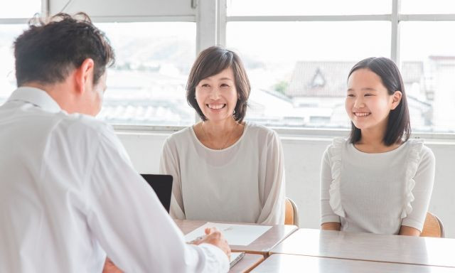 写真：保護者と学生と先生が和やかに面談している。