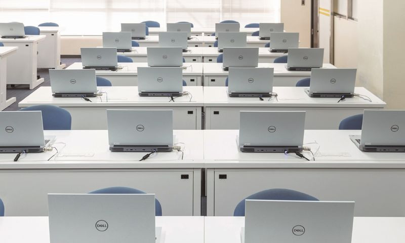 写真：202実習室。机がたくさん並んでおり、机の上にはノートパソコンが置かれている。