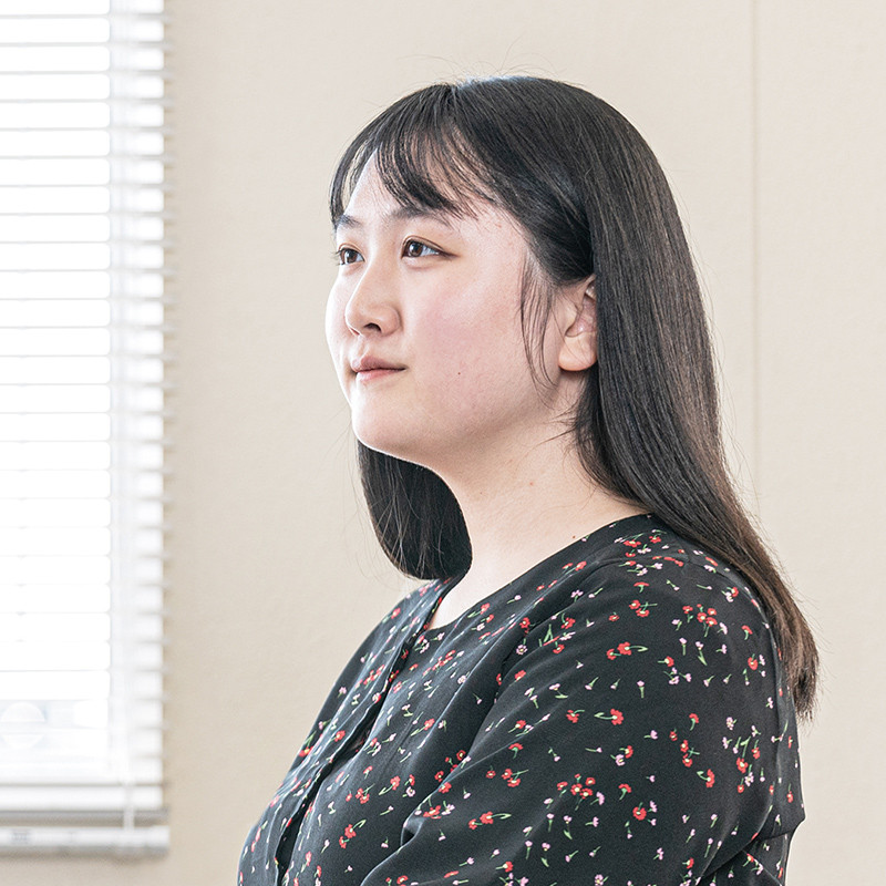 写真：花柄の黒い服を着たロングヘアーの女子学生