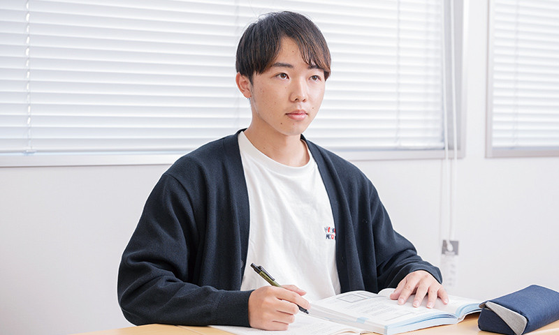 写真：テキストとノートを広げ、真剣な表情で勉強をしている北野さん