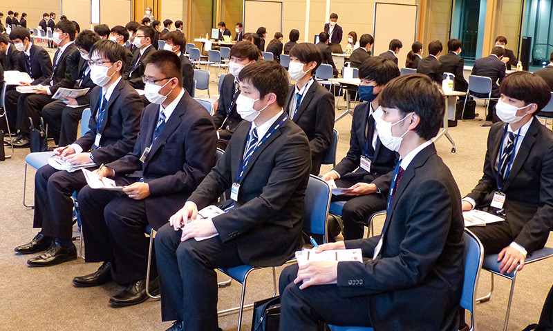 写真：KCS合同企業説明会の様子。スーツを着たたくさんの学生が会場で企業説明を聞いている。