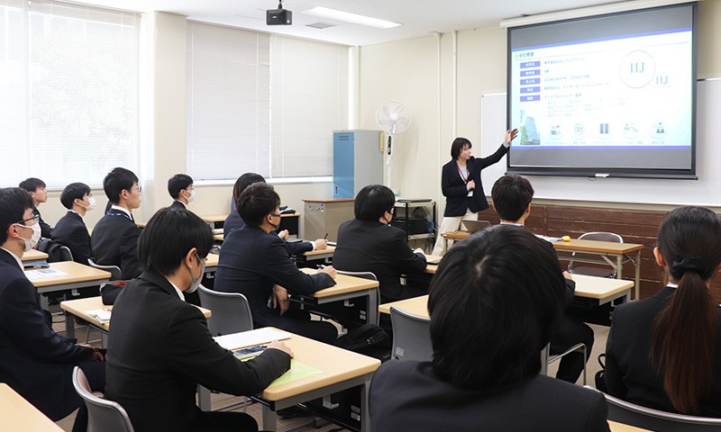 写真：KCS合同企業説明会の様子。スーツを着たたくさんの学生が会場で企業説明を聞いている。