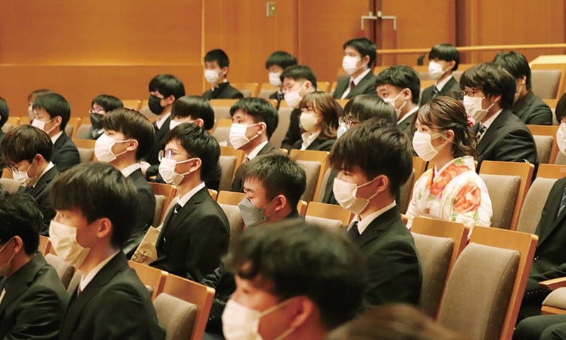 写真：KCS卒業式の様子。学生が卒業証書を受け取っている。